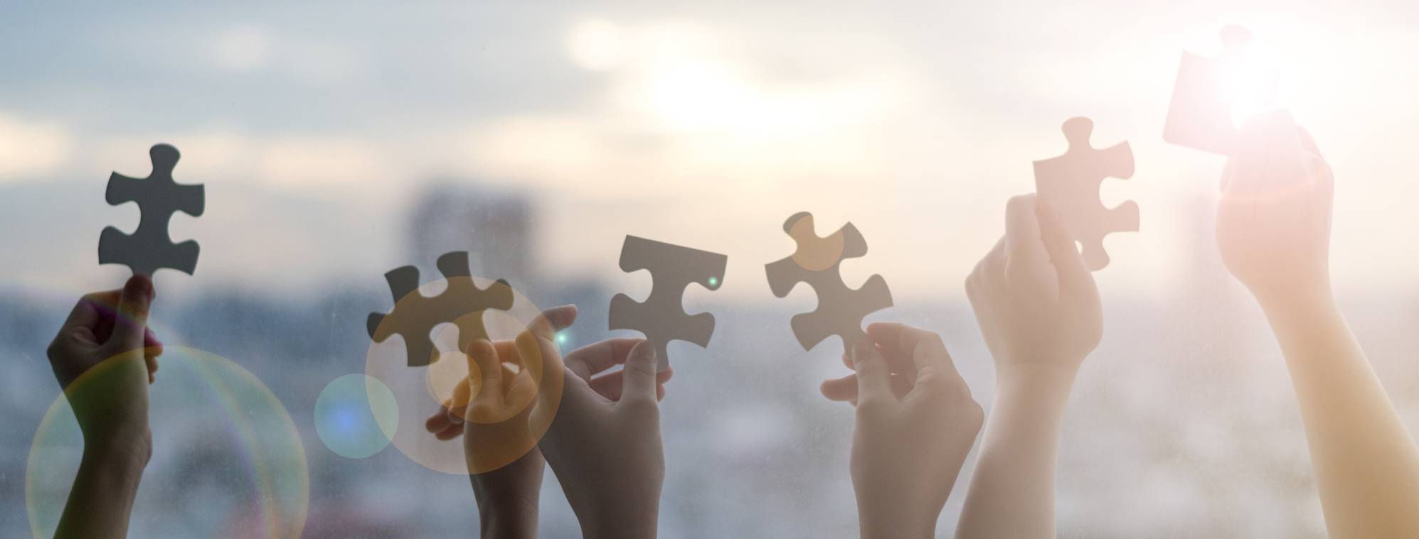 Hands holding puzzle pieces to symbolize working together with autism.